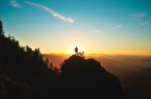Man standing on a hill at sunset: Hold firmly to the gospel message